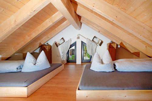two beds in a room with wooden ceilings at Schorenmoos Lodge in Dietmannsried
