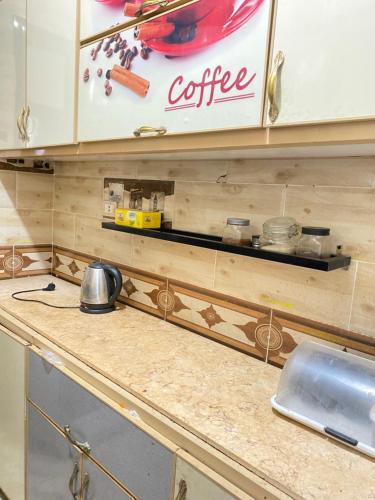 a kitchen counter with a coffee sign on the wall at Cozy Private Apartment in Asyut