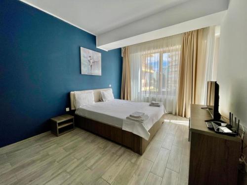 a bedroom with a bed and a blue wall at Catalina Summerland Apartaments Mamaia Nord in Mamaia