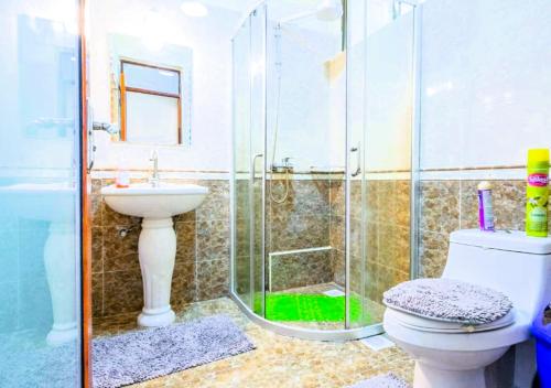 y baño con ducha, aseo y lavamanos. en Tribal Themed 3BR Penthouse en Nairobi