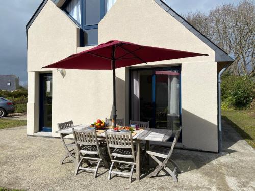 une table et des chaises avec un parasol rouge dans l'établissement La Bigorne, à Fouesnant