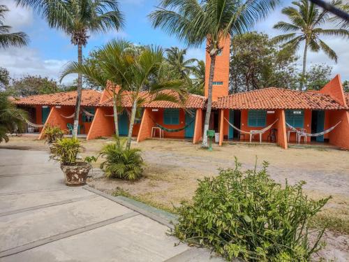 an orange house with palm trees in front of it at Pousada Tupi Imbassai in Imbassai