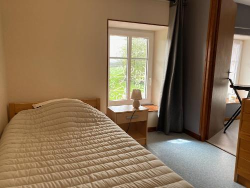 een slaapkamer met een groot bed en een raam bij Aux Trois Gîtes in La Chapelle