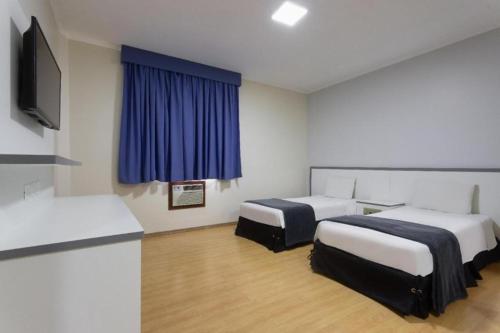 サンパウロにあるカリヨン プラザ ホテルのベッド2台とテレビが備わるホテルルームです。