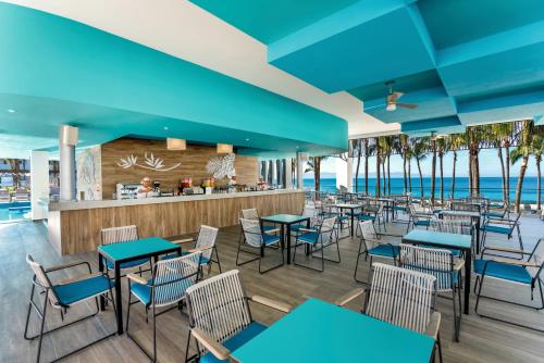 a restaurant with blue tables and chairs and the beach at Riu Vallarta - All Inclusive in Bucerías