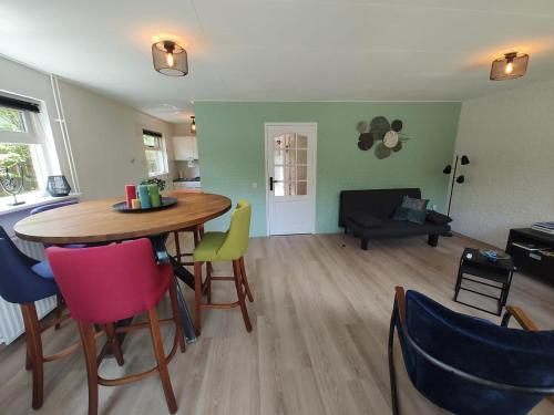 cocina y sala de estar con mesa y sillas en Vakantiehuis op rustig bospark Veluwe en Voorthuizen