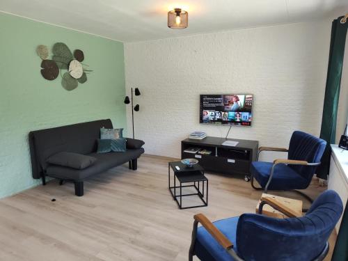 a living room with a couch and chairs at Vakantiehuis met privetuin op rustig bospark Veluwe in Voorthuizen