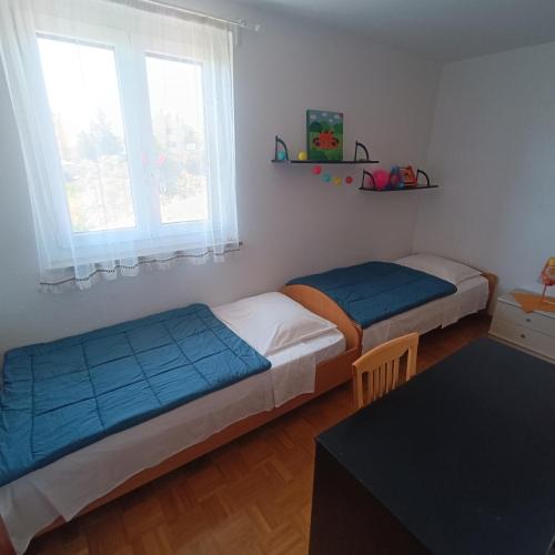 2 camas en una habitación con mesa y 2 ventanas en Luna 31, en Portorož