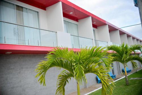 un edificio con dos palmeras delante en hotel quatro coracoes, en Arapiraca