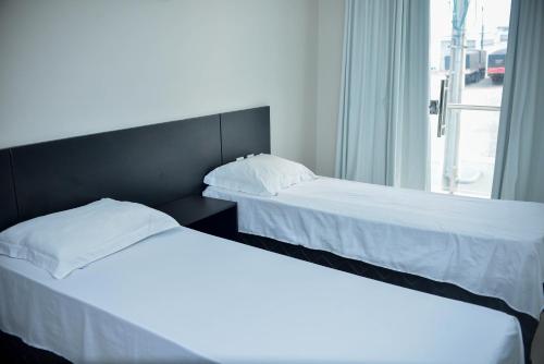 hotel quatro coracoes في أرابيراكا: سريرين يجلسون بجانب بعض في غرفة