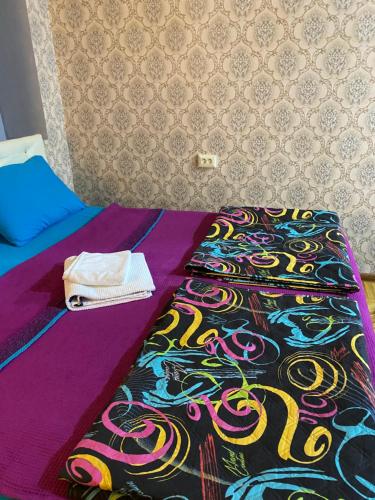 a bed with a colorful comforter and a towel on it at Anna'S Home in Kutaisi