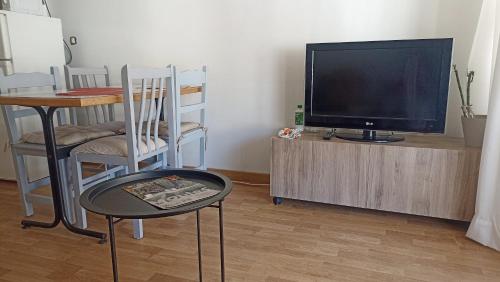 Illes medes في لو ايسترتيت: غرفة معيشة فيها تلفزيون وطاولة وكراسي