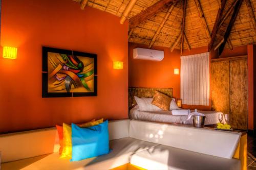 1 dormitorio con 1 cama en una habitación con paredes de color naranja en Yemaya Boutique Hotel en Canoas en Canoas de Punta Sal