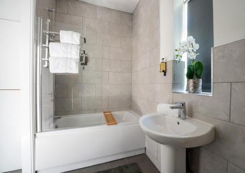 ein weißes Badezimmer mit einer Badewanne und einem Waschbecken in der Unterkunft Tettenhall Lodge Apartment in Wolverhampton