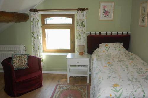 a bedroom with a bed and a chair and a window at Le Buisson B&B in Gouvy