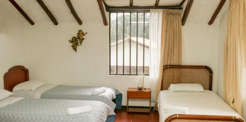 - une chambre avec 2 lits, une fenêtre et une table dans l'établissement Casa Campestre Villa Cecilia, à Villa de Leyva