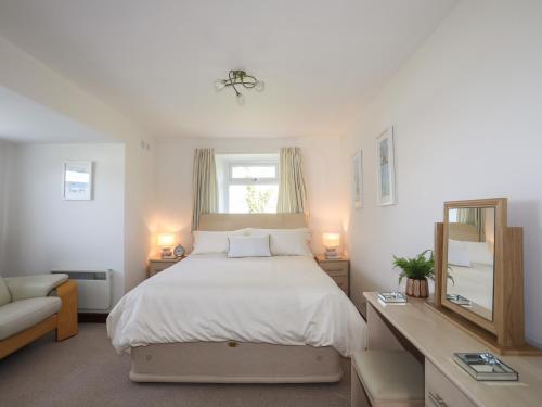 1 dormitorio con cama, escritorio y espejo en The Farmhouse, en Pwllheli