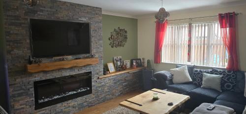 sala de estar con TV y chimenea de ladrillo en Family home, en Johnston