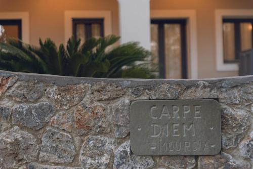 a sign on a stone wall with the words cape drew house at Carpe Diem Moursia Studio in Liapades