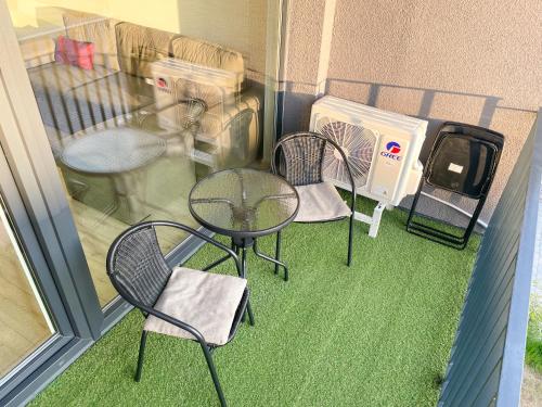 a patio with three chairs and a table on a balcony at Duneville Apartments Mano Jūra 2 in Palanga