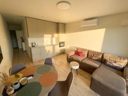uma sala de estar com uma mesa e um sofá em Duneville Apartments Mano Jūra 2 em Palanga