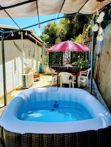 a hot tub in a yard with a table and an umbrella at Bungalow Sixdays 3 in Camporosso