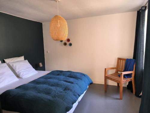 - une chambre avec un lit doté d'une couverture bleue et d'une chaise dans l'établissement Ancien hôtel baie Saint-Michel-en-Grève, à Saint-Michel-en-Grève