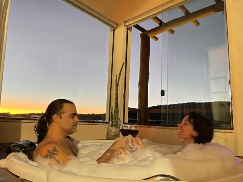 a man and a woman in a bath tub with a cat at Chalé Jenipapo in Serra do Cipo