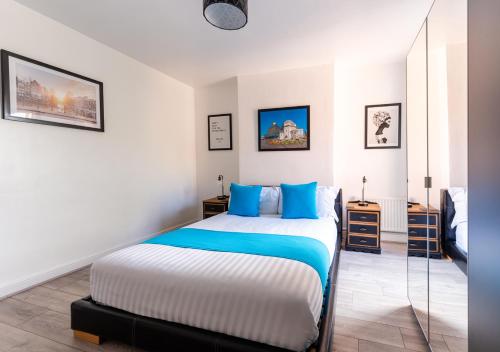 um quarto com uma cama grande e almofadas azuis em Tettenhall Lodge Apartment em Wolverhampton