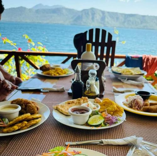 a table with plates of food on a table with the ocean at Posada Ecologica La Abuela in La Laguna