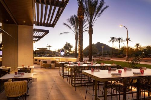 a restaurant with tables and chairs and palm trees at Caesars Republic Scottsdale, a Hilton Hotel in Scottsdale