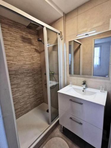 une salle de bain avec une douche, un lavabo et un miroir dans l'établissement Résidence Le Carlton - Appartement deux pièces cabine 4 couchages à Port Leucate. Réf: 2CAR_331AC MAE-2271, à Leucate