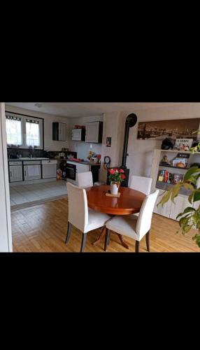 - une cuisine avec une table en bois et des chaises blanches dans l'établissement Maison 2 chambres, à Saint-Léonard-de-Noblat
