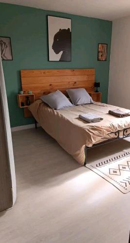 Ce lit se trouve dans une chambre dotée d'un mur vert. dans l'établissement Maison 2 chambres, à Saint-Léonard-de-Noblat