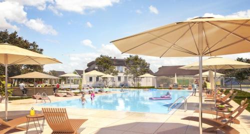 a swimming pool with chairs and umbrellas at Stilo Country Dargobądz in Wolin