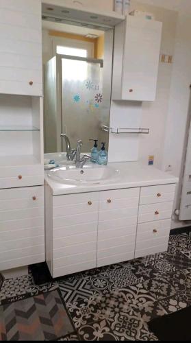 une salle de bain blanche avec un lavabo et un miroir dans l'établissement Maison 2 chambres, à Saint-Léonard-de-Noblat
