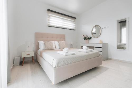 a white bedroom with a bed and a mirror at Zante Melina's Apartment in Argasi