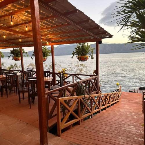 a wooden deck with tables and chairs next to the water at Posada Ecologica La Abuela in La Laguna