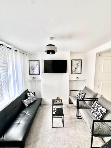 uma sala de estar com um sofá preto e uma televisão de ecrã plano em Gillingham 4 bed Guest House em Gillingham
