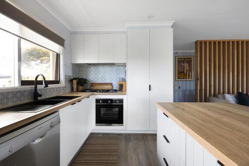 a kitchen with white cabinets and a wooden counter top at Deluxe family home near beach with views sleeps 10-12 in Ocean Grove