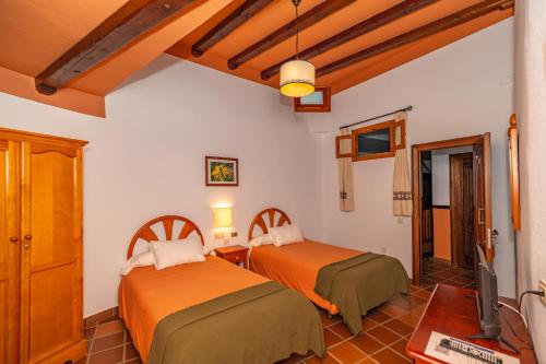 a bedroom with two beds and a tv in it at Hotel La Fragua I in Trevélez