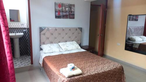 een slaapkamer met een bed, een wastafel en een spiegel bij Hospedaje Roma in Huánuco