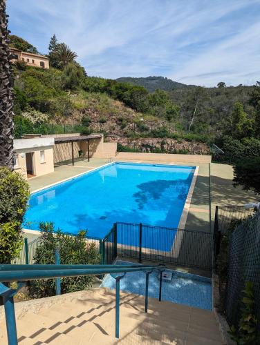une grande piscine bleue avec une colline en arrière-plan dans l'établissement Appartement avec vue mer exceptionnelle dans résidence de standing, au calme, avec piscine, à Mandelieu-la-Napoule