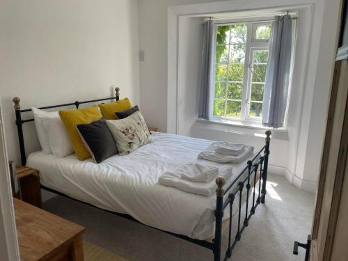 Un dormitorio con una cama con almohadas y una ventana. en The Farmhouse, Fowey, en Fowey