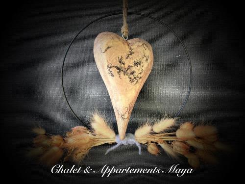 een houten hart hangend aan een rooster met veren bij Chalet Maya in Schladming