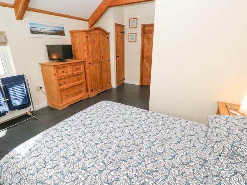 a bedroom with a bed and a dresser and a television at Godolphin Barn in Helston