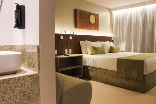 a bedroom with a bed and a bathroom with a sink at Smart Hotel João Pessoa in João Pessoa