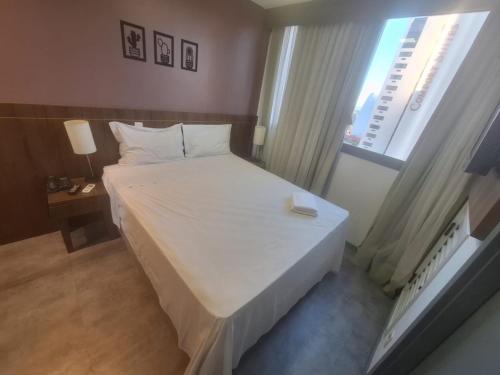 Hóspede já Nobile suites في برازيليا: غرفة نوم بسرير ابيض ونافذة
