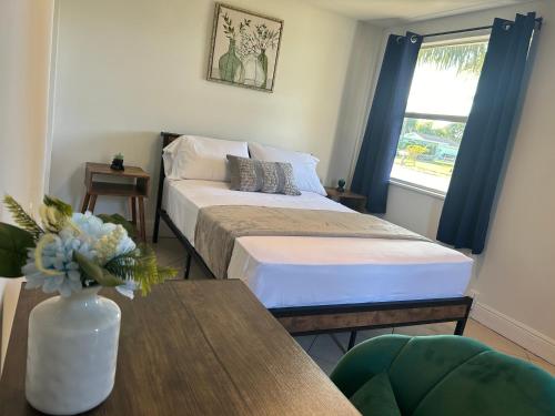 Private Rooms in West Palm Beach - Next to Airport في ويست بالم بيتش: غرفة نوم مع سرير و مزهرية من الزهور على طاولة