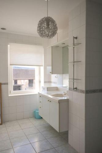 a white bathroom with a sink and a window at Le Petit Luquis - maison de campagne 7 chambres - in Chézy-sur-Marne